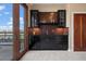 Wet bar with dark cabinetry, granite countertops, and glass shelving at 2245 Blake St # L M N, Denver, CO 80205