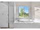 Bathroom featuring tub with large window, glass-enclosed shower and tile surround at 2600 Reserve Ct, Erie, CO 80516