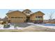 Charming tan house with well-kept landscaping, stone accents, and a concrete driveway with snow at 2600 Reserve Ct, Erie, CO 80516