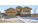 Charming tan house with well-kept landscaping, stone accents, and a concrete driveway with snow at 2600 Reserve Ct, Erie, CO 80516