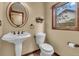 Bathroom features a pedestal sink, toilet, decorative mirror, and window with outdoor views at 1665 W 113Th Ave, Denver, CO 80234