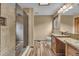 Bathroom features granite countertops, wooden cabinets, walk-in shower, and wood look floor tiles at 1665 W 113Th Ave, Denver, CO 80234