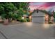 Charming home boasts a spacious driveway leading to an attached two-car garage, framed by lush landscaping at dusk at 1665 W 113Th Ave, Denver, CO 80234