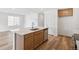Bright kitchen featuring a center island with a sink and stainless steel dishwasher, complemented by wood-look flooring at 9283 Biscay St, Commerce City, CO 80022