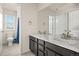 Bathroom featuring a double sink vanity with marble countertop, decorative mirror, and an adjacent powder room at 840 Avena Dr, Elizabeth, CO 80107