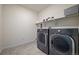 Well-lit laundry room featuring sleek, gray front-load washer and dryer set and shelf at 840 Avena Dr, Elizabeth, CO 80107