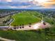 Breathtaking aerial view of a lush community park with a lake, walking paths, and distant city skyline at 9266 E 35Th Ave, Denver, CO 80238