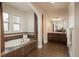 Bathroom showcasing a soaking tub with tile surround, double sinks, and natural light from the windows at 9266 E 35Th Ave, Denver, CO 80238