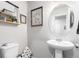 Cozy powder room featuring a pedestal sink, decorative mirror, and charming wall art at 10 N Quantock St, Aurora, CO 80018