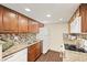 Well-lit kitchen with wood cabinetry, granite countertops, and modern appliances at 3400 S Eagle St # 104, Aurora, CO 80014