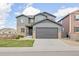 Charming two-story home with a gray exterior, stone accents, manicured lawn, and a two-car garage at 880 Mcmurdo Cir, Castle Rock, CO 80108