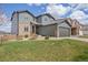 Charming two-story home with a gray exterior, stone accents, manicured lawn, and a two-car garage at 880 Mcmurdo Cir, Castle Rock, CO 80108