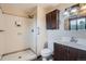 Well-lit bathroom with a walk-in shower, wood vanity, and decorative mirror at 30839 Manitoba Dr, Evergreen, CO 80439