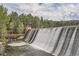 Scenic view of the dam waterfall and water spilling into the river, with a bridge for pedestrians to cross at 30839 Manitoba Dr, Evergreen, CO 80439