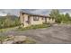 Exterior view of a charming single-story home with wood siding, a gravel driveway, and a serene natural setting at 30839 Manitoba Dr, Evergreen, CO 80439