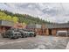 Rustic restaurant with wooden facade and ample parking, nestled against a backdrop of lush green trees and cloudy skies at 30839 Manitoba Dr, Evergreen, CO 80439