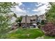 Aerial view of the backyard showcasing a lush lawn, patio area, mature trees, and surrounding residences at 573 Entrada Dr, Golden, CO 80401