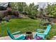 Beautifully landscaped backyard with a lush lawn, mature trees, and colorful Adirondack chairs around a fire pit at 573 Entrada Dr, Golden, CO 80401