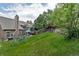 Spacious backyard featuring a lush green lawn, mature trees, a play structure, and a cozy patio area at 573 Entrada Dr, Golden, CO 80401
