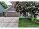 Charming home exterior with a two-car garage, lush lawn, and a mature tree providing shade and curb appeal at 573 Entrada Dr, Golden, CO 80401