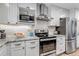 Well-lit kitchen features stainless steel appliances, white cabinets, stylish countertops, and subway tile backsplash at 573 Entrada Dr, Golden, CO 80401