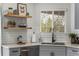 Kitchen features grey cabinets, stainless appliances, white subway tile, floating wood shelves and wood floor at 4043 E Geddes Cir, Centennial, CO 80122