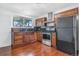 Traditional kitchen with wood cabinets, stainless steel appliances, dark counters and hardwood floors at 11976 E Arizona Dr, Aurora, CO 80012