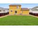 Large backyard featuring a well-maintained lawn and a charming yellow two-story house at 25812 E Cedar Pl, Aurora, CO 80018