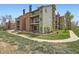 Exterior view of condo buildings featuring balconies, green siding, and brick accents surrounded by grassy areas at 4899 S Dudley St # 15G, Littleton, CO 80123