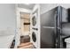 Compact laundry area with stacked washer/dryer, black fridge, and a bathroom featuring a black and white tile shower at 4899 S Dudley St # 15G, Littleton, CO 80123