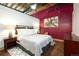 Bedroom with dark wood furniture, exposed pipes and ductwork, and a bright red accent wall at 1143 Auraria Pkwy # 203, Denver, CO 80204