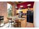 Modern kitchen with brick wall, light wood cabinets, granite countertops, and stainless steel appliances at 1143 Auraria Pkwy # 203, Denver, CO 80204