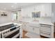 Bright kitchen with white cabinets, a farmhouse sink, and stainless steel appliances and hardwood floors at 1661 Oneida St, Denver, CO 80220