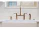 Close-up of a modern kitchen sink with brushed gold faucet and white subway tile backsplash at 1661 Oneida St, Denver, CO 80220