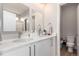 Bright bathroom featuring double sinks, white cabinetry, modern fixtures, and a glimpse into the shower area at 551 S Main St, Byers, CO 80103