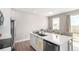 Modern kitchen island with white countertops, stainless steel appliances, and a bright dining area with large window at 551 S Main St, Byers, CO 80103