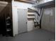 Unfinished basement with painted concrete walls and floor with door and shelving for storage at 8160 S Fillmore Cir, Centennial, CO 80122