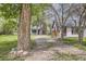 Charming exterior view featuring a gravel driveway and mature trees surrounding the home at 1115 W Quincy Ave, Englewood, CO 80110