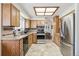 Well-lit kitchen with stainless steel appliances, tile flooring, and light wood cabinets for ample storage at 7681 S Jellison St, Littleton, CO 80127