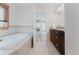 Bathroom featuring a tiled soaking tub, dark wood vanity, and an open doorway to the bedroom at 2034 Newton St, Denver, CO 80211