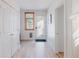 Well-lit hallway with white trim, hardwood floors, and access to a door with glass panel at 2034 Newton St, Denver, CO 80211