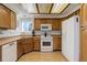 Functional kitchen with wooden cabinets, white appliances, and ample counter space with modern flooring at 15099 E Wagontrail Pl, Aurora, CO 80015