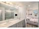 Bathroom with double vanity, quartz countertop and gray cabinets, connects to ensuite bedroom at 11132 Via Lata Dr, Broomfield, CO 80020