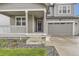 Inviting front porch, gray facade with stone accents, attached two car garage, and manicured landscaping at 1420 E Witherspoon Dr, Elizabeth, CO 80107