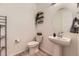 Stylish powder room with pedestal sink, decorative shelves, and modern fixtures at 1420 E Witherspoon Dr, Elizabeth, CO 80107