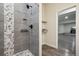 Close-up of a tiled walk-in shower with sleek fixtures and pebble tile details at 1180 Antelope W Dr, Bennett, CO 80102