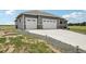 Three-car garage and driveway of home with a landscaped front yard and stone accents at 1180 Antelope W Dr, Bennett, CO 80102