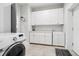 Spacious laundry room featuring white cabinets, quartz countertops, and modern washer at 1180 Antelope W Dr, Bennett, CO 80102