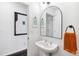 Stylish half-bathroom with pedestal sink, modern mirror, and decorative wall art, complemented by clean white walls at 2706 Blake St, Denver, CO 80205