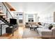 Modern open living room with a large sectional sofa, hardwood floors, and a staircase with metal railings at 2706 Blake St, Denver, CO 80205